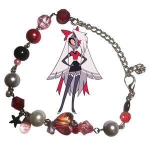 May include: A silver chain bracelet with red, pink, black, and white beads, a star charm, and a heart charm. The bracelet also features a small silver clasp.