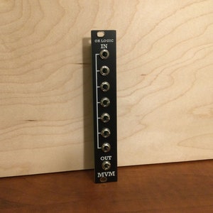 May include: Black Eurorack module with the text "OR LOGIC" and "IN" and "OUT" and "MVVM" printed on it. The module has eight 1/4 inch jacks.