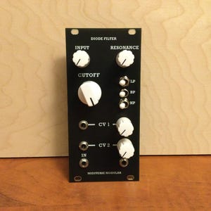 May include: Black synthesizer module with white knobs and labels. The labels read "DIODE FILTER", "INPUT", "RESONANCE", "CUTOFF", "LP", "BP", "HP", "CV 1", "CV 2", "IN", and "MIDIVERSE MODULAR".
