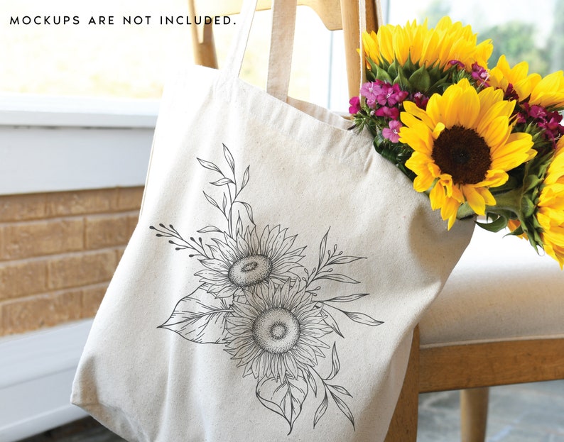K&ouml;nnte beinhalten: Eine wei&szlig;e Canvas-Tragetasche mit einer schwarzen Linienzeichnung von Sonnenblumen und Bl&auml;ttern. Die Tasche liegt auf einem Holzstuhl mit einem Strau&szlig; gelber Sonnenblumen im Hintergrund.