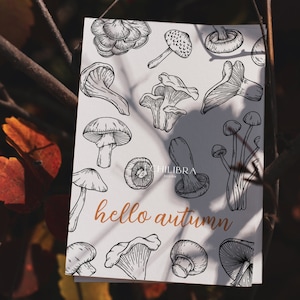 Puede incluir: Una tarjeta blanca con una ilustraci&oacute;n en blanco y negro de setas y el texto "hello autumn".