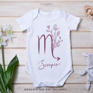 Puede incluir: Un body blanco para beb&eacute; con un dise&ntilde;o floral burdeos y el s&iacute;mbolo del zod&iacute;aco de Escorpio. El texto "Scorpio" est&aacute; escrito en cursiva debajo del s&iacute;mbolo.
