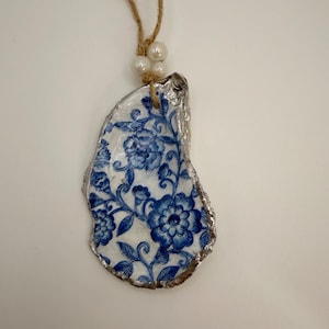 Ostra natural decorada con la técnica del decoupage y adornos de flores azules y blancas.
