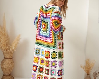 Könnte beinhalten: Ein langer, weißer Häkelcardigan mit einem bunten Granny-Square-Muster. Der Cardigan hat einen V-Ausschnitt und lange Ärmel.