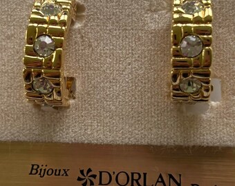Op de afbeelding: Een paar gouden creolen met heldere strass steentjes. De oorbellen zijn van het merk "Bijoux D'Orlan Paris".