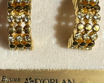 Op de afbeelding: Een paar gouden creolen met heldere strass steentjes. De oorbellen zitten in een doosje met de tekst "Bijoux D'ORLAN Paris".