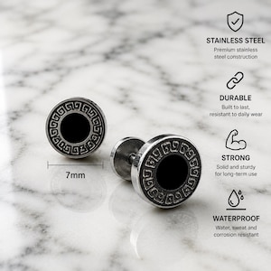 May include: Two round stainless steel stud earrings featuring a black center and a silver-toned Greek key border. The earrings measure 7mm in diameter. Text on the image highlights features: STAINLESS STEEL, DURABLE, STRONG, and WATERPROOF.