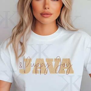 Puede incluir: Camiseta blanca con el texto "& Puppy Joy" en letras doradas y "JAVA" en escritura marrón.