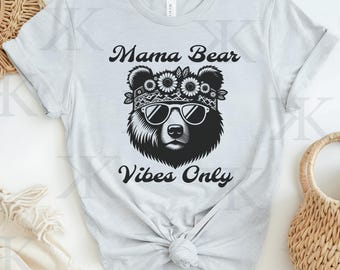 May include: Gray t-shirt with a black and white illustration of a bear wearing a flower crown and sunglasses. The text "Mama Bear Vibes Only" is printed below the bear.