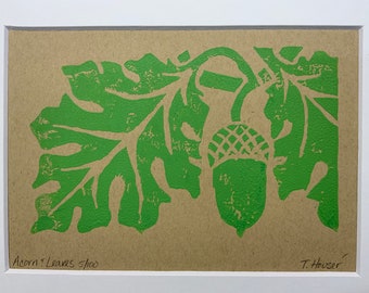 May include: Green linocut print of an acorn and leaves on a brown paper background. The print is signed "T. Houser" and numbered "5/100".