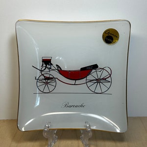 May include: A white square glass ashtray with a gold rim. It features a black and red illustration of a horse-drawn carriage with the word "Barouche" printed below. The Chance Glass logo is in the top right corner.