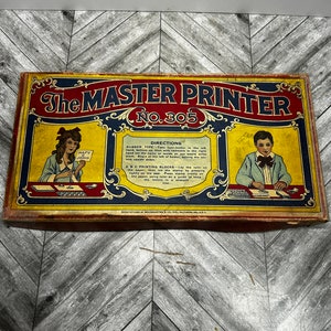 May include: Vintage box for a Master Printer toy set, No. 305. The box is yellow with red and blue trim. It features illustrations of children using the toy to print names. The box has directions for using the toy.