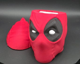 Puede incluir: Porta pañuelos de cabeza de Deadpool rojo y negro. El porta pañuelos está hecho de plástico y tiene un diseño realista.