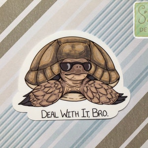 May include: A brown tortoise wearing sunglasses and a relaxed expression. The tortoise is sitting on a white background with the text "Deal With It, Bro." printed below it.