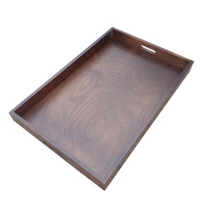 May include: A rectangular wooden serving tray with a dark brown finish. The tray has two cut-out handles on the sides.