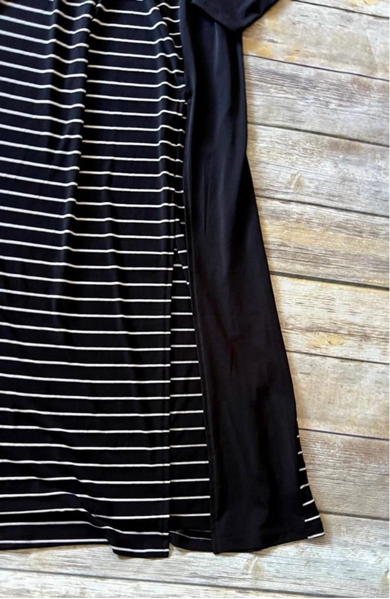 May include: A black and white striped dress with a solid black panel on the side. The dress has horizontal white stripes on a black background. The fabric appears to be soft and flowing.