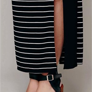 May include: A black and white striped maxi dress with a high side split. The dress is worn with black leather sandals with a buckle fastening and a block heel.