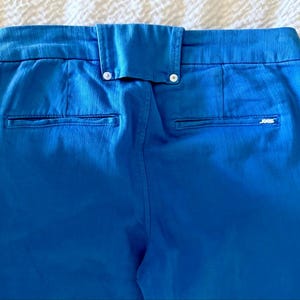 Pode incluir: Close-up da parte de tr&aacute;s de cal&ccedil;as azuis. As cal&ccedil;as t&ecirc;m dois bolsos traseiros e uma cintura com fecho de bot&atilde;o. O tecido tem uma textura subtil. A marca "JOES" &eacute; vis&iacute;vel no bolso direito.