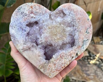 May include: A heart-shaped amethyst geode with a large, open cavity filled with sparkling purple crystals. The geode is surrounded by a layer of white and pink agate.