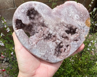 May include: A heart-shaped amethyst geode with a natural, raw exterior and a hollow interior lined with sparkling purple crystals.