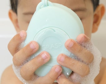 Pebbl silicone bath and shower brush. Dispenses and lathers soap. Helps child gently scrub body and hair. Builds dexterity & motor skills.