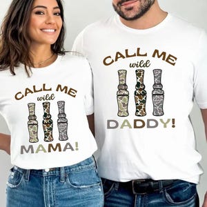 Puede incluir: Dos camisetas blancas con un estampado de camuflaje marr&oacute;n y verde de llamadas de pato. El texto en las camisetas dice "Call me wild" y "Daddy!" o "Mama!"