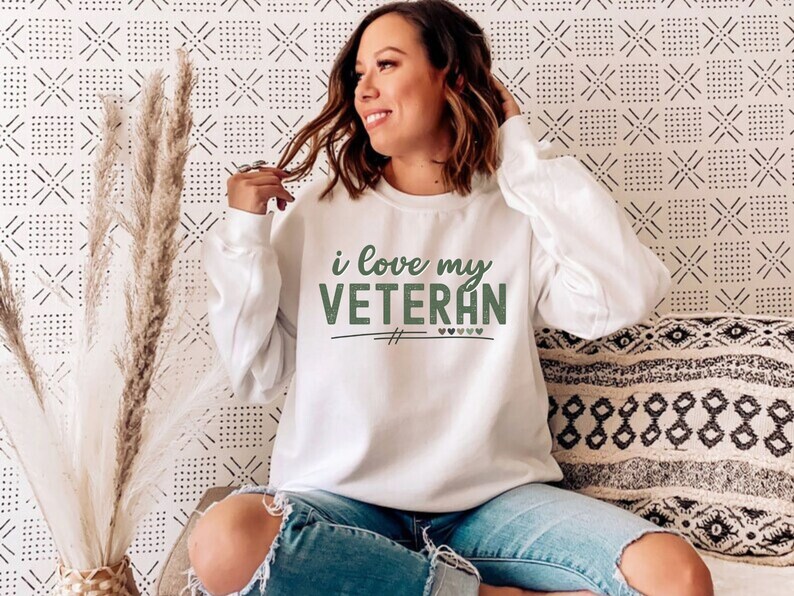 Pu&ograve; includere: Felpa bianca con il testo "i love my VETERAN" in lettere verdi con piccoli cuori verdi.