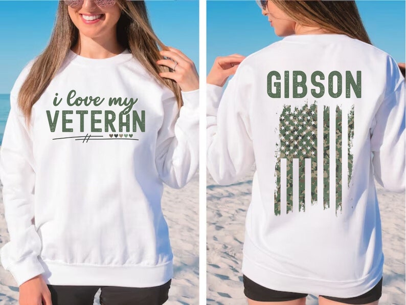 Pu&ograve; includere: Felpa bianca con il testo "i love my VETERAN" sul davanti e il testo "GIBSON" con una bandiera americana mimetica sul retro.
