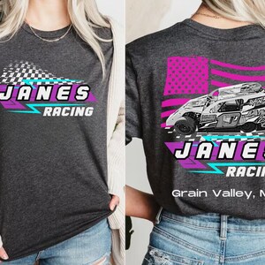 Peut inclure: Un t-shirt gris avec un motif blanc et rose repr&eacute;sentant une voiture de course, un drapeau &agrave; damier et le texte "Janes Racing". Le dos du t-shirt pr&eacute;sente un drapeau am&eacute;ricain rose et blanc, une voiture de course et le texte "Janes Racing Grain Valley, MO".