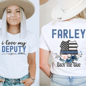 Pode incluir: Camiseta branca com o texto "i love my DEPUTY" na frente e o texto "FARLEY Back The Blue" com um distintivo de pol&iacute;cia azul e branco e um design floral nas costas.