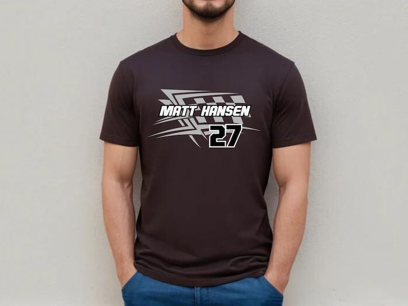 Może przedstawiać: Czarny t-shirt z białym nadrukiem przedstawiającym flagę w kratkę i tekst "MATT HANSEN 27".