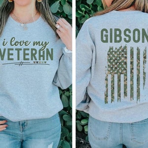 Pu&ograve; includere: Una felpa grigia con la scritta "i love my VETERAN" sul davanti e una bandiera americana mimetica con la scritta "GIBSON" sul retro.