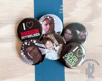 Peut inclure: Un ensemble de cinq badges ronds épinglés représentant des personnages de Star Wars. Deux badges affichent du texte : l'un indique I heart Anakin Skywalker en rouge, l'autre I heart Obi-Wan Kenobi en vert. Trois badges présentent des portraits.