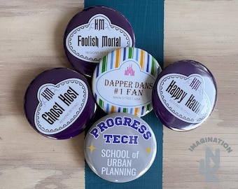 Peut inclure: Cinq badges ronds avec des motifs variés. Deux badges violets portent le texte "HM Foolish Mortal" et "HM Ghost Host". Un badge violet indique "Happy Haunt". Un badge rayé affiche "Dapper Dans #1 Fan". Un badge gris indique "Progress Tech School of Urban Planning".