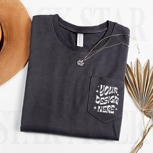 May include: A dark gray t-shirt with a pocket on the left side. The pocket has the text "YOUR DESIGN HERE" printed on it in white.