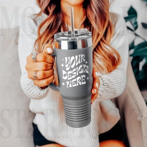 May include: Gray stainless steel tumbler with a handle and a lid. The tumbler has a white design that says "Your design here".