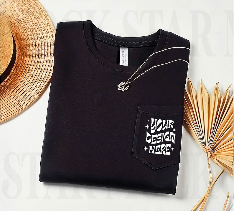 Op de afbeelding: Zwart T-shirt met een zakje aan de linkerkant. Het zakje heeft witte tekst die zegt "YOUR DESIGN HERE".