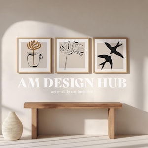 May include: Three framed art prints with minimalist botanical designs in neutral tones. The prints feature line art of a flower, a leaf, and birds. Below the artwork is a wooden bench and a decorative vase. The text "AM DESIGN HUB" is displayed.