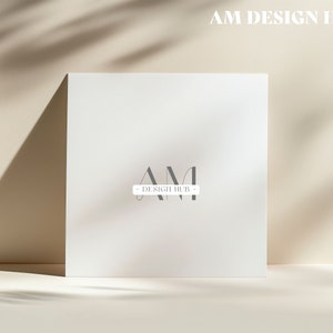 May include: A white card with the text "AM DESIGN HUB" in black letters. The letters "AM" are stylized and overlap each other.