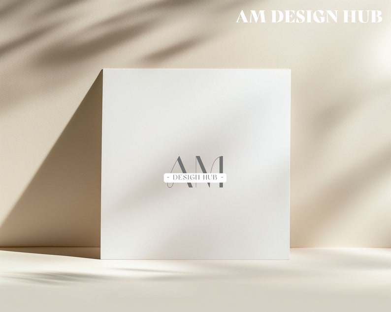 May include: A white card with the text "AM DESIGN HUB" in black letters. The letters "AM" are stylized and overlap each other.