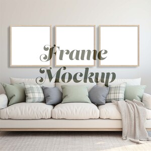 May include: Three square picture frames with white mats and light wood frames are hanging on a white wall above a white couch with light green, gray, and plaid pillows. The couch has a white throw blanket draped over the back. The text "Frame Mockup" is superimposed over the image.