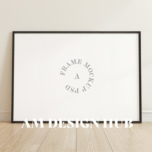 May include: A black frame mockup with a white background. The text "FRAME MOCKUP PSD" is written in a circle in the center of the frame. The text "AM DESIGN HUB" is written below the frame.