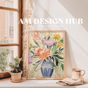 May include: A framed watercolor painting of a bouquet of flowers in a blue and white vase. The flowers are pink, yellow, orange, and white. The painting is on a white wall with a window and a potted plant in the background. The text "AM DESIGN HUB" and "artwork is not included" is visible at the top of the image.