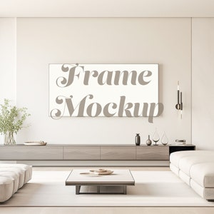 May include: A white frame mockup in a modern living room setting. The frame is hanging on a light beige wall above a long wooden cabinet. The cabinet is decorated with vases, plants, and other decorative items. A white couch is in the foreground, and a coffee table with a tray of decorative items is in the center of the room.