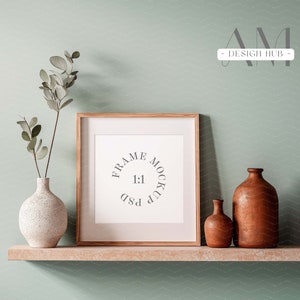 May include: A wooden frame mockup with a white mat and a white background. The frame is sitting on a wooden shelf with two ceramic vases, one white and one brown.