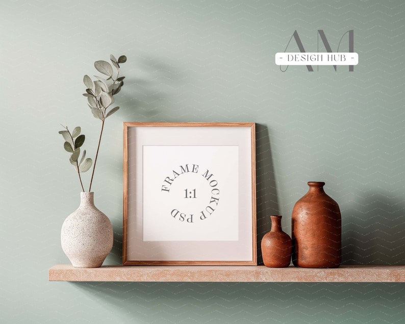May include: A wooden frame mockup with a white mat and a white background. The frame is sitting on a wooden shelf with two ceramic vases, one white and one brown.