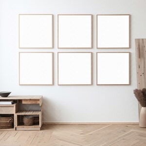 May include: Six empty picture frames with light wood frames are arranged in a grid on a white wall. A wooden shelf with two baskets sits below the frames. A vase with dried pampas grass sits on the floor to the right of the shelf.