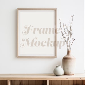 May include: A wooden frame mockup with a white background, a vase with dried branches and white flowers, and a smaller vase on a wooden shelf.