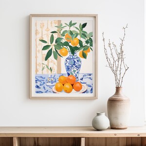 May include: A framed painting of a still life with a blue and white porcelain vase filled with orange blossoms and oranges on a blue and white tablecloth.