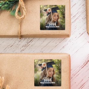 K&ouml;nnte beinhalten: Ein Graduation-Geschenk-Etikett mit einem Foto einer jungen Frau, die eine Kappe und eine Robe tr&auml;gt. Das Etikett tr&auml;gt den Text "Class of 2025 Congratulations Bella".
